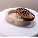 3D-printed oval soap dish with drain rack, white and wood-look.