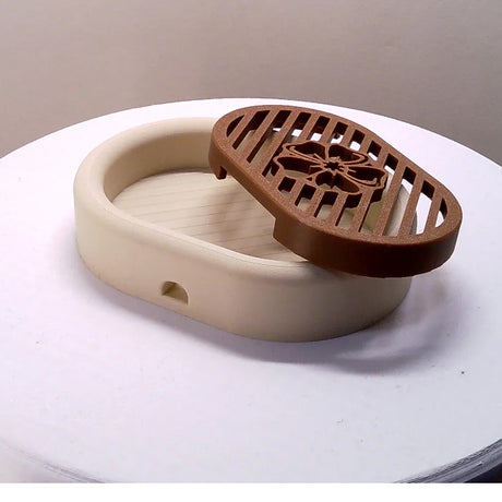 3D-printed oval soap dish with drain rack, white and wood-look.